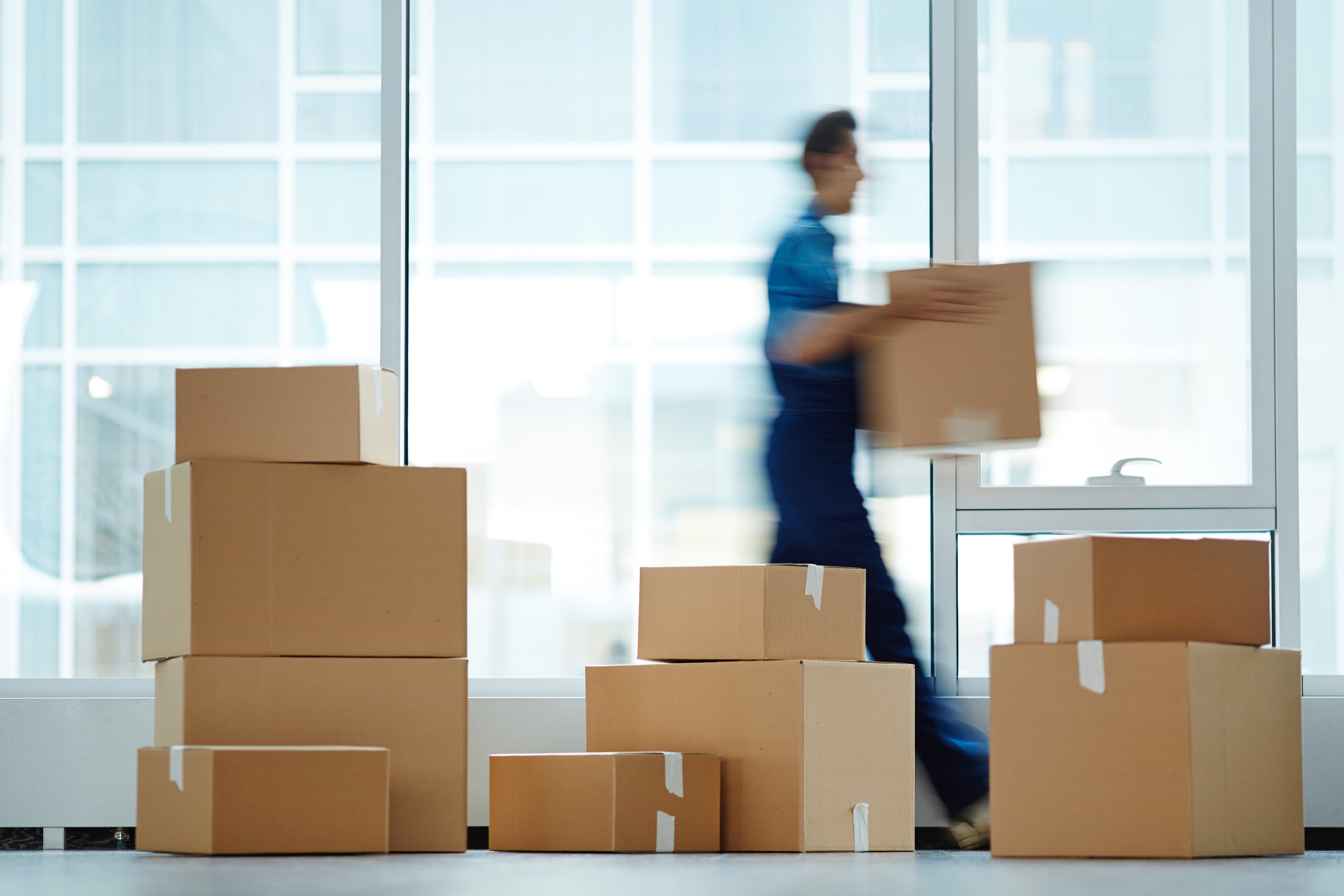 Arbeiter trägt Umzugskartons in modernem Büro